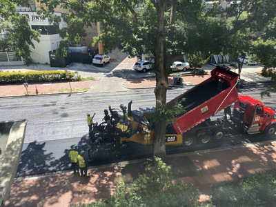 The asphalt is dumped into the hopper of the Caterpillar machine that then lays a nice smooth surface on the road.